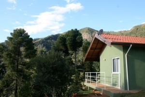 una casa verde con balcone con vista sulle montagne sullo sfondo di Abrigo da Reserva a Santo Antônio do Pinhal Altre 45 foto