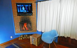 sala de estar con chimenea, TV y silla en Pousada Portal Dos Ventos, en Visconde De Maua