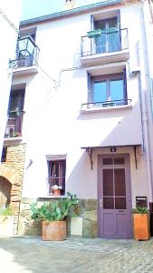 un edificio blanco con puerta morada y 2 balcones en Le Cosy Elne, en Elne