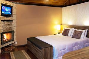 a bedroom with a bed and a fireplace at Pousada Portal Dos Ventos in Visconde De Maua