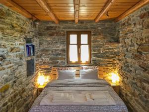 ein Schlafzimmer mit einem Bett in einer Steinmauer in der Unterkunft Under Royal Oaks in Péra Meriá