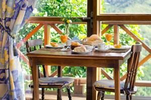a wooden table with food on it with two chairs at Pousada Portal Dos Ventos in Visconde De Maua