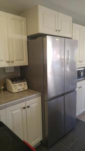a stainless steel refrigerator in a kitchen with white cabinets at La Maison du Village, spa in Shawinigan