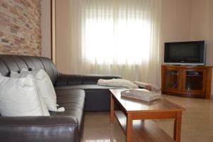 sala de estar con sofá de cuero y TV en Piso da Empegada, en Arzúa