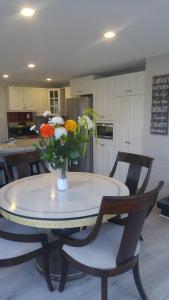 a kitchen with a table with a vase of flowers on it at La Maison du Village, spa in Shawinigan +28 photos