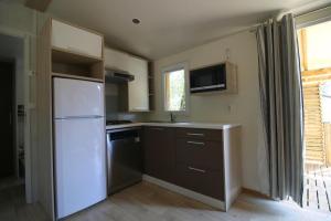 uma cozinha com um frigorífico branco e uma janela em camping mas du sartre em Auriolles