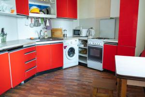 een keuken met rode kasten en een wasmachine bij Panorama-hostel in Kiev