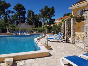 a swimming pool with blue and white chairs next to a house at PERE in Korčula