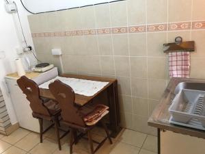 eine Küche mit einem Tisch, 2 Stühlen und einem Waschbecken in der Unterkunft Vila Regina in Palić