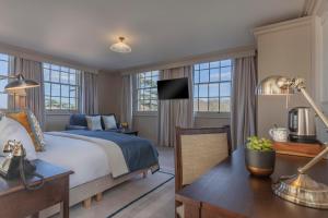a bedroom with a bed and a desk and windows at Richmond Hill Hotel in Richmond upon Thames