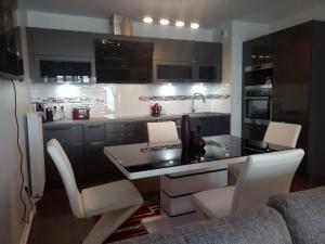 a kitchen with black and white cabinets and white chairs at Bel appartement T2 près du lac avc un parking privé in Bordeaux