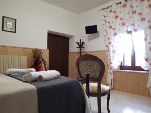 een slaapkamer met een bed, een stoel en een raam bij B&B Il Cardellino in Porano