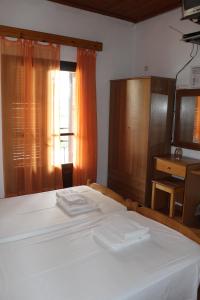 Un dormitorio con una gran cama blanca y una ventana en Smile 2, en Kassiopi