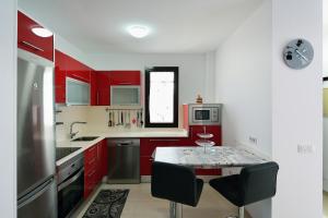 eine Küche mit roten Schränken und einem Tisch mit Stühlen in der Unterkunft Villa Victoria in Playa Blanca