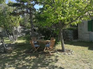une table et des chaises sous un arbre dans une cour dans l'établissement House Kaja, à Jablanac