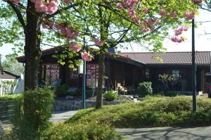 a house with pink flowering trees in front of it at Ferienwohnung Blockhaus Juka in Vinningen