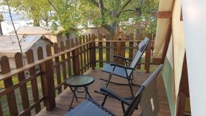 a deck with chairs and a table and a fence at Parco Del Lago Glamping And Lodges in Anguillara Sabazia