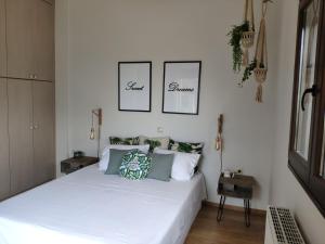 a bedroom with a white bed with two pictures on the wall at Olive Tree Cottage 2 in Nea Peramos