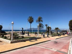 a park with palm trees and people walking on a sidewalk at Apartamentos casa Tia Antonia in Málaga
