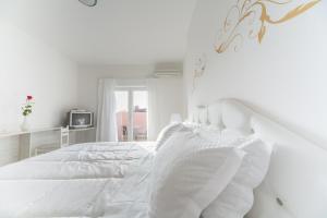 a white bedroom with a white bed and a window at Hotel La Settima Luna in Savudrija