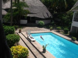 un par de personas en una piscina en Papillon Garden Bar Villas, en Bamburi
