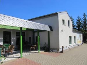 ein weißes Gebäude mit grünen Säulen und einer Terrasse in der Unterkunft Pension Anni in Sanitz
