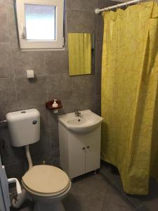 a bathroom with a toilet and a yellow shower curtain at Twins V.V.T Hostel in Orešani
