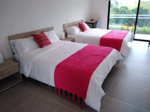 2 camas con sábanas rojas y blancas en una habitación en Hotel Boutique La Ceiba en Quimbaya