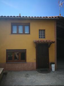 a yellow house with a door and a window at Casa Nueva in Salas