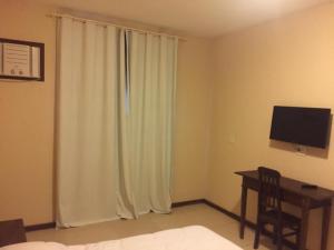 a bedroom with a bed and a desk with a television at Hotel Fazenda Mangalarga in Paty do Alferes