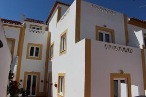 uma fila de casas brancas com acabamentos castanhos em Guest House - Duna Parque Group em Vila Nova de Milfontes