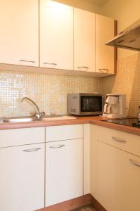 a kitchen with white cabinets and a microwave at Studio Algarve in Middelkerke