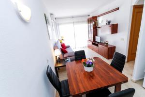 a dining room with a wooden table and chairs at AQUAMARINA A HomeStay By Turismar in La Pineda