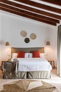 1 dormitorio con 1 cama blanca grande con almohadas rojas en Curolla Petit Hotel, en Maria de la Salut