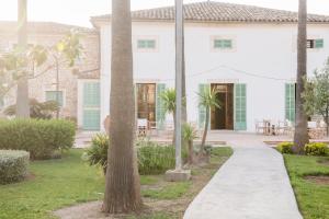 a walkway in front of a house with palm trees at Curolla Petit Hotel in Maria de la Salut
