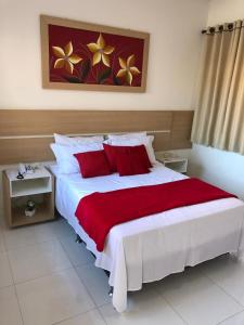 a bedroom with a large white bed with red pillows at POUSADA LUNARA in Jequié
