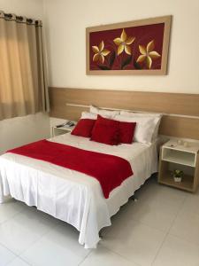 a bedroom with a large bed with red pillows at POUSADA LUNARA in Jequié