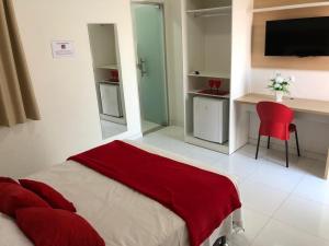 a bedroom with a bed and a desk and a red chair at POUSADA LUNARA in Jequié