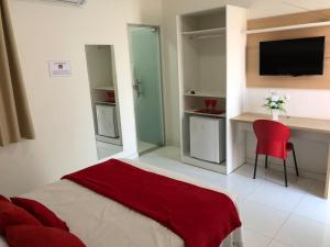 a bedroom with a bed and a desk and a red chair at POUSADA LUNARA in Jequié