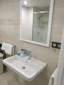 y baño con lavabo blanco y espejo. en Apartamentos Las Palmeras, en Palma del Río