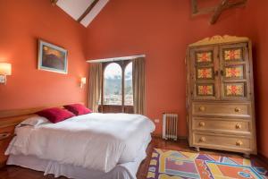 a bedroom with orange walls and a bed and a dresser at SAUCE Hotel Boutique in Ollantaytambo