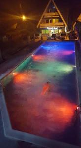 una piscina con luces de colores en el agua por la noche en Pensiunea La Castel - Piscina incalzita, en Costinesti