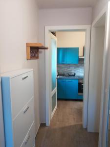 uma pequena cozinha com armários azuis e um frigorífico branco em Studio apartman Arni em Rijeka