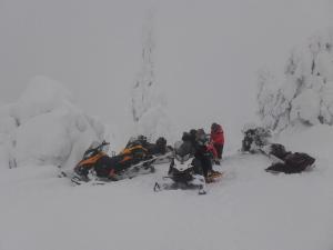 Eine Gruppe von Menschen, die im Schnee sitzen in der Unterkunft Ollilan Lomamajat in Kuusamo