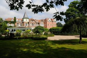 a large brick building with a tower on top of a yard at Kasteel Wurfeld in Maaseik