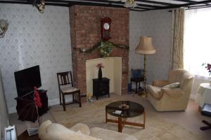 a living room with a couch and a clock on the wall at Little Mermaid Cottage in Dawlish