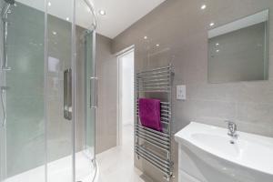 a bathroom with a glass shower and a sink at Childs Hill Vacation Home in London