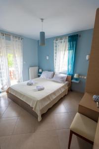 a bedroom with a bed with blue walls and windows at House Christie in Chrysi Ammoudia