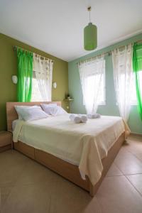 a bedroom with a large bed with green walls and windows at House Christie in Chrysi Ammoudia