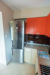 a kitchen with a stainless steel refrigerator and red cabinets at House Christie in Chrysi Ammoudia
